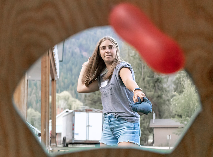 Carnival Games, girl throwing into bean bag toss hole