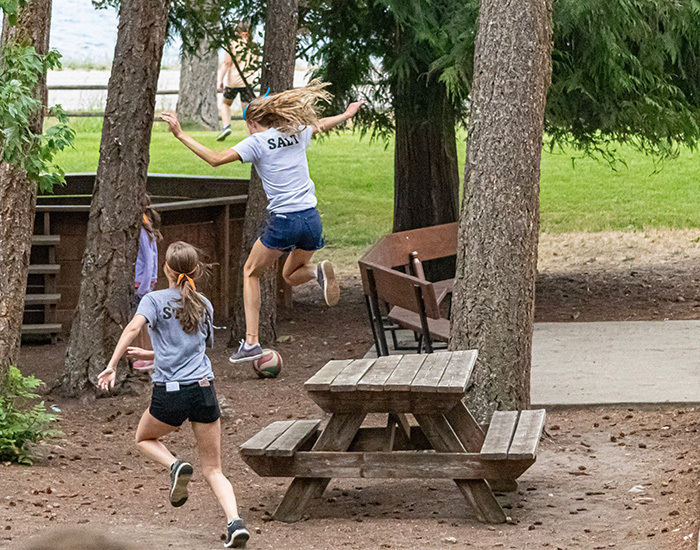 Playing Headhunters, girl jumping off the picnic table